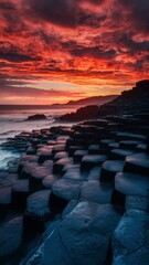 The bright colors of the sunset on the Giant's causeway, the sky glowing orange and red, the columns casting long shadows on the rugged coastline.