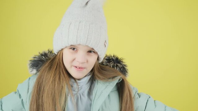 Little girl in a green down jacket and hat surprised excitedlooks opening her mouth in amazement, shouting Wow, astonished by sudden shocking news, expressing disbelief and smiles at the camera, on a 