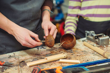 Creative student doing his project in workshop. Boy in the workshop makes crafts with coconut. School, development and learning concept.