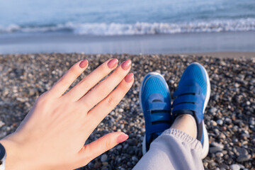 Hand with Pink Glitter Nail Polish Relaxing at the Beach. Close-up of a hand with pink glitter nail polish.