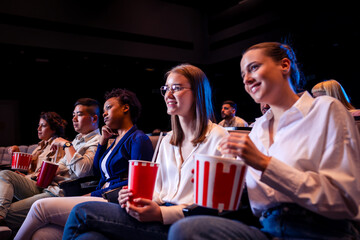 People are watching a movie in cinema. They are eating popcorn and drinking juices