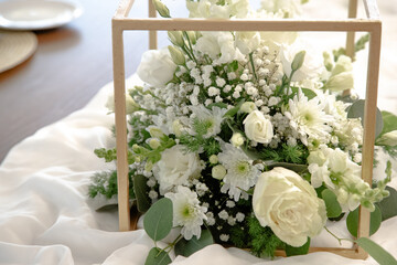 A beautiful floral centerpiece with white roses, daisies, gypsophila and greenery, elegantly...