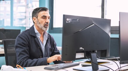 Businessman using computer at desk in creative workspace