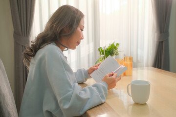 Woman reading a book in the living room While there was a coffee cup on the table.