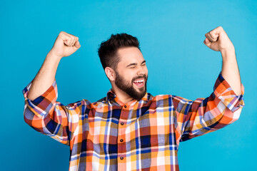 Portrait of nice young man raise fists wear shirt isolated on blue color background