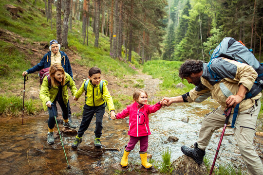 Multi-generational family crossing a stream during a forest hike
