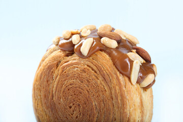 One supreme croissant with chocolate paste and nuts on light blue background, closeup. Tasty puff pastry