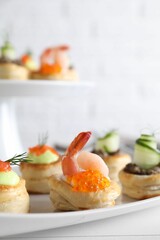 Different delicious puff pastry snacks on white table