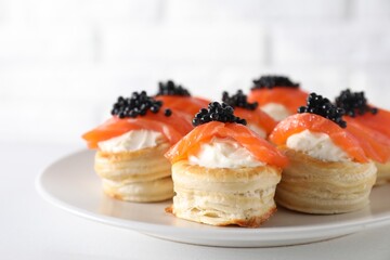 Delicious puff pastry with cream cheese, salmon and black caviar on white table, closeup