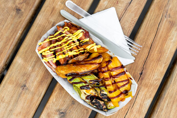 Loaded fries with melted cheese and various toppings on a wooden table.