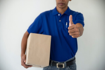 Delivery man holding Parcel Box Package to deliver and giving thumb up. Courier hand carries the...