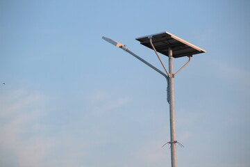 a solar-powered street light with a clear blue sky background.
