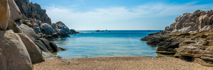 Panorama of a scenic beach cove (Cala di l'Ea) between rocks on the mediterranean coast in Capo Testa, Sardinia web banner, Italy