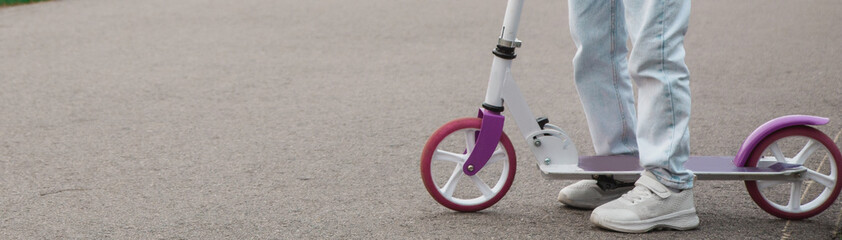 Obraz premium Child riding scooter. Active outdoor fun for kids. Summer sports for preschool children. Little girl in spring park.