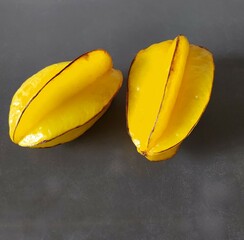 carambola fruit, isolated, clos-up. two fresh ripe whole yellow fruits on a gray table background.