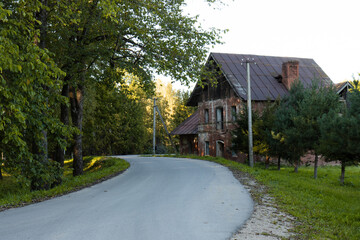 An old brick cottage on the edge of the forest. The road to the old cottage.