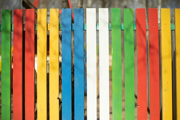 Colored fence made of wood. Boards of different colors. Cheerful hedge. Yard Details.