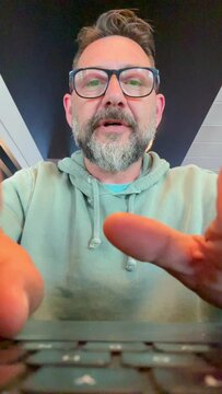 Laptop camera view pov of adult man at work on computer writing and typing on keyboard with concentrated expression. People online work. Workplace and modern businessman. Emails notification message