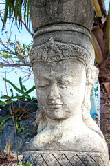 Obraz premium The ancient stone Buddha statue in the tropical garden adds a serene and peaceful atmosphere