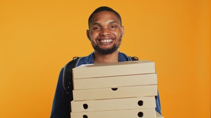 African american pizzeria deliveryman holding stack of pizza boxes to deliver food order to...