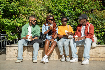 Calm contented black students, men, women, resting outside together after classes, chatting,...