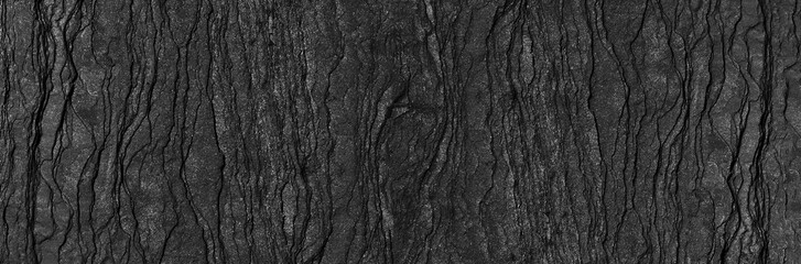 Black rock texture background. Rough mountain surface with cracks. Close-up. Dark gray stone basalt background. Panorama 