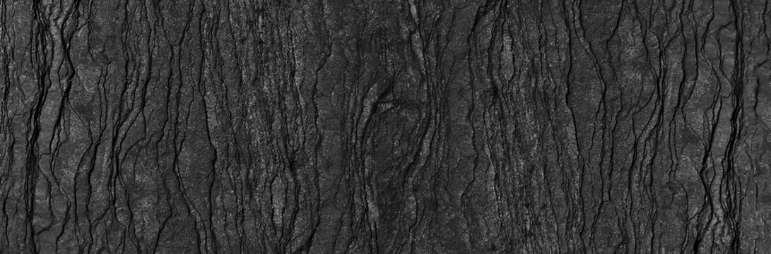 Black rock texture background. Rough mountain surface with cracks. Close-up. Dark gray stone basalt background. Panorama 