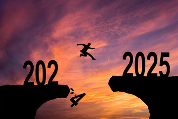 Man jumping on cliff 2025 over the precipice with stones at amazing sunset. New Year's concept....