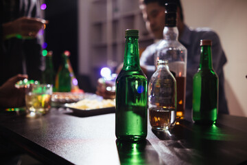 In the background, many bottles of alcohol were placed on the table at the party. Bottles of...
