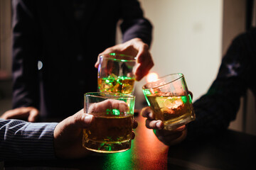 A group of businessmen held brandy glasses together to cheers glasses of brandy after concluding negotiations on business ventures and reaching a satisfactory agreement for joint business profits.