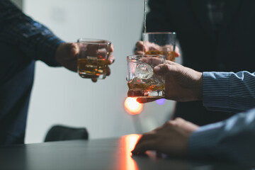 A group of businessmen held brandy glasses together to cheers glasses of brandy after concluding...