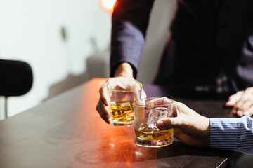 A group of businessmen held brandy glasses together to cheers glasses of brandy after concluding negotiations on business ventures and reaching a satisfactory agreement for joint business profits.