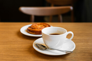 Pain aux raisins, bun with raisins and a cup of coffee on wooden table