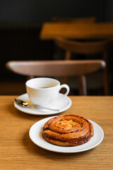 Pain aux raisins, bun with raisins and a cup of coffee on wooden table