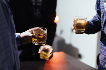 A group of businessmen held brandy glasses together to cheers glasses of brandy after concluding...