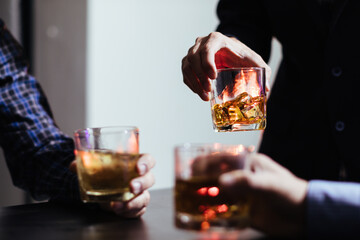 A group of businessmen held brandy glasses together to cheers glasses of brandy after concluding negotiations on business ventures and reaching a satisfactory agreement for joint business profits.