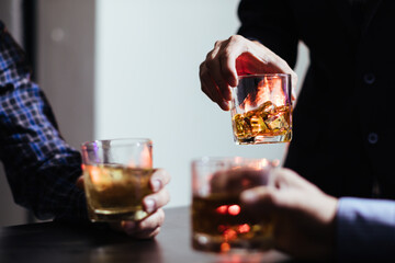 A group of businessmen held brandy glasses together to cheers glasses of brandy after concluding...