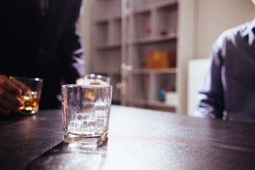 brandy glass that is kept on table in office is a glass of brandy that business people often drink after working hours to let the alcohol help them relax. Concept of relaxing with alcoholic beverages