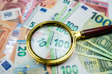 magnifying glass on different euro bills as background. Finance concept