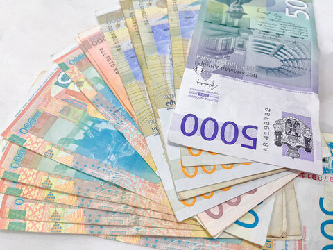 A colorful array of Serbian banknotes, arranged in a fan shape on a textured surface.