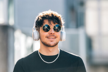 young man with headphones on the street wearing sunglasses