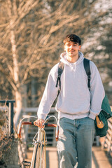 young man or student on the street with vintage bicycle walking, vertical
