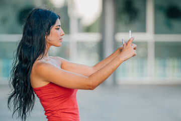young latin girl or woman with summer clothes looking at her mobile phone or smartphone