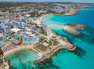 Aerial view of famous Nissi Beach with hotels and the island. Sandy beach and turquoise Mediterranean sea. Panoramic coastline view towards Ayia Napa town.