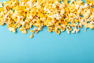 Delicious popcorn on a blue background. Cinema and entertainment concept. Movie night with popcorn. Cheese and caramel popcorn. Delicious appetizer, snack. Place for text. Copy space.Banner