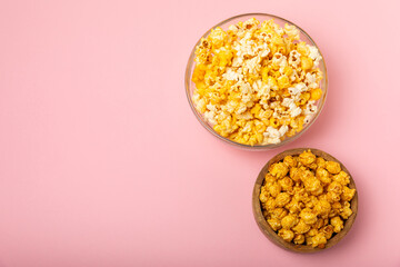 Delicious popcorn in a bowl on a pink background. Cinema and entertainment concept. Movie night with popcorn. Cheese and caramel popcorn. Delicious appetizer, snack. Place for text. Copy space.Banner