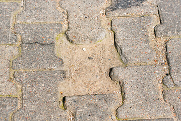 Defects on paving slabs. Sidewalk with pothole. Inferior or insufficient bedding sand might cause pavers to move and break. Paving failure; improperly laid paving stones