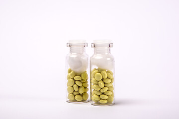 Two medicine bottles with yellow pills on white background, treatment and health