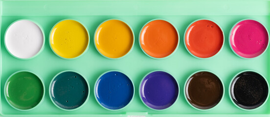 Background of twelve colors of watercolor paints.