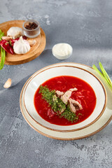 Classic beetroot borscht with beef and a dollop of sour cream, presented in a speckled bowl on a grey textured backdrop
